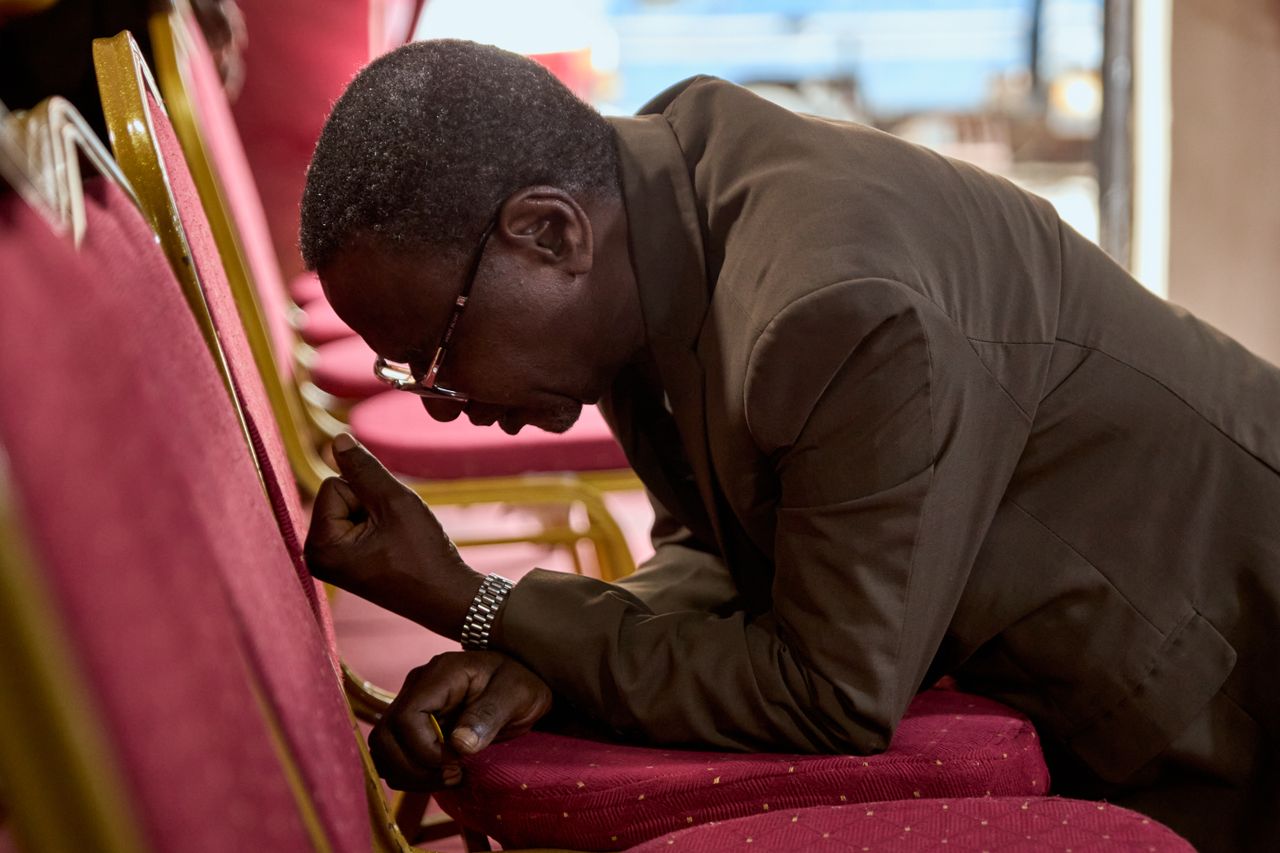 A man kneels in prayer in a church, displaying devotion and faith.